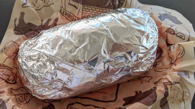 A burrito wrapped in foil in a Chipotle wrapper