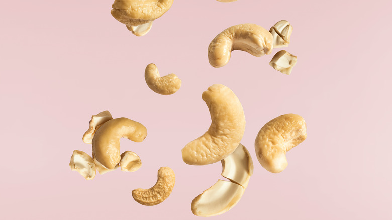 Cashews falling on pink background