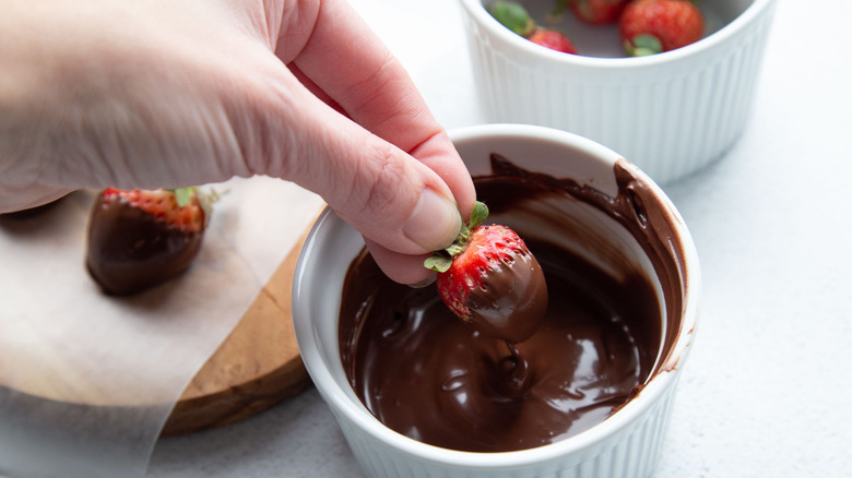 hand dipping strawberries in chocolate