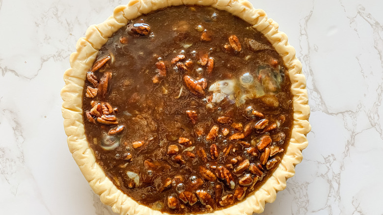 Pie batter poured over pecans