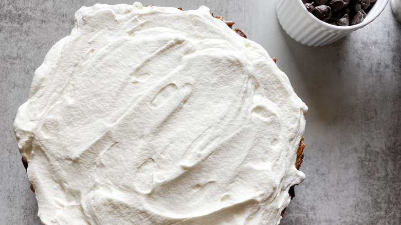 frosted chocolate praline layer cake with a dish of chocolate chips nearby