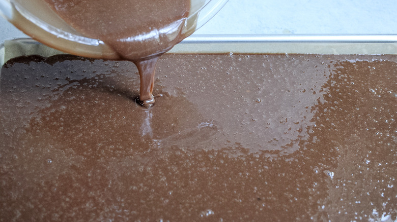 pouring cake batter in a pan 