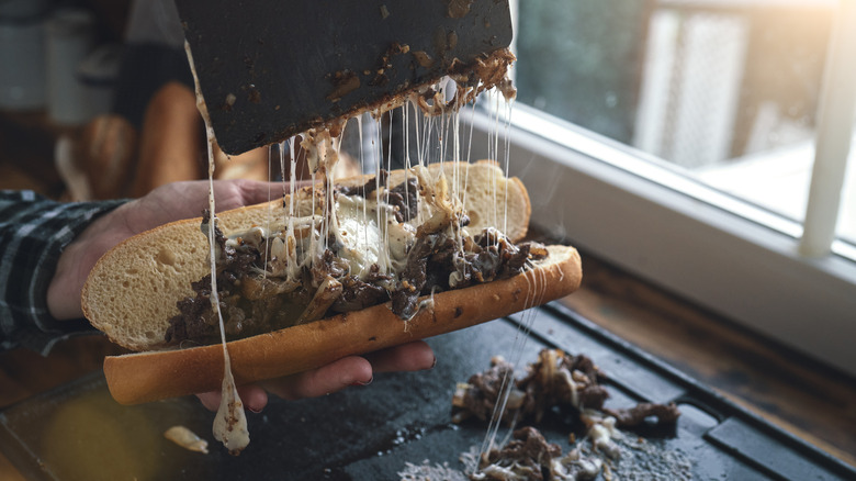 Hand filling roll with Philly cheesesteak