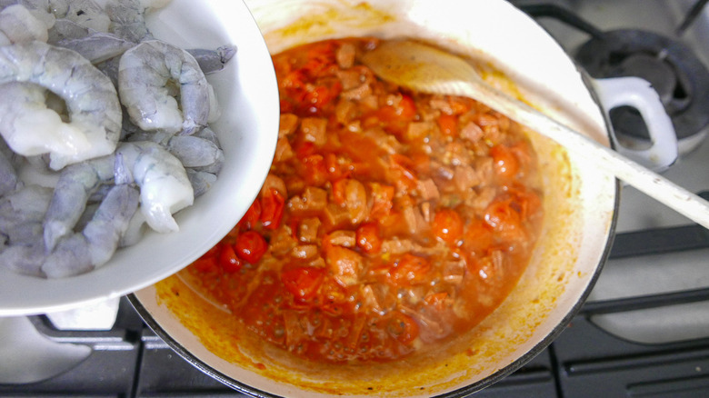 prawns being added to chorizo and tomatoes