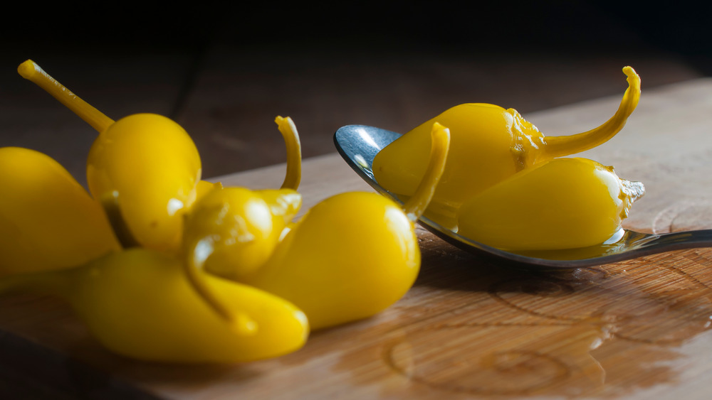 Yellow pepperoncinis on a wood board