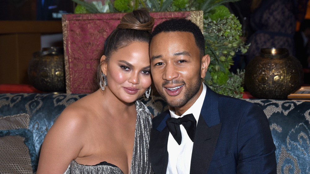 Chrissy Teigen, John Legend sitting at a dinner