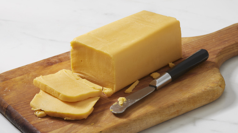 Block of cheddar on wooden board