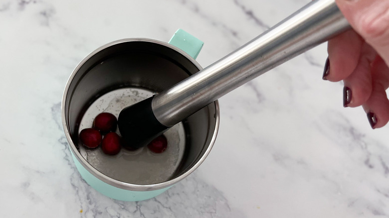 muddling cranberries in a mug