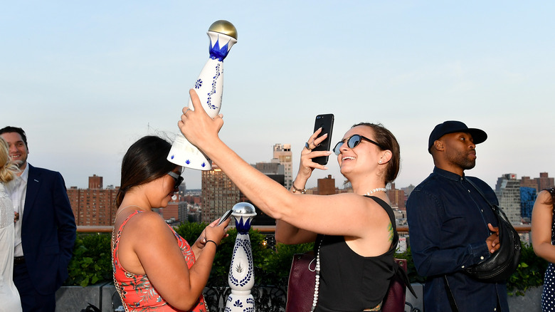 Lady taking picture of tequila bottle