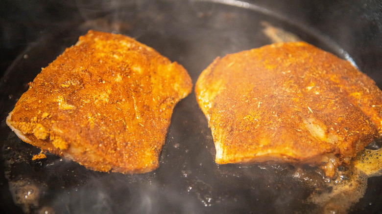 Blackened fish cooking in a cast iron skillet