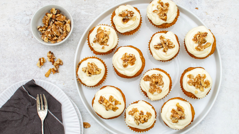 carrot cake cupcakes with cream cheese frosting and walnuts on plate