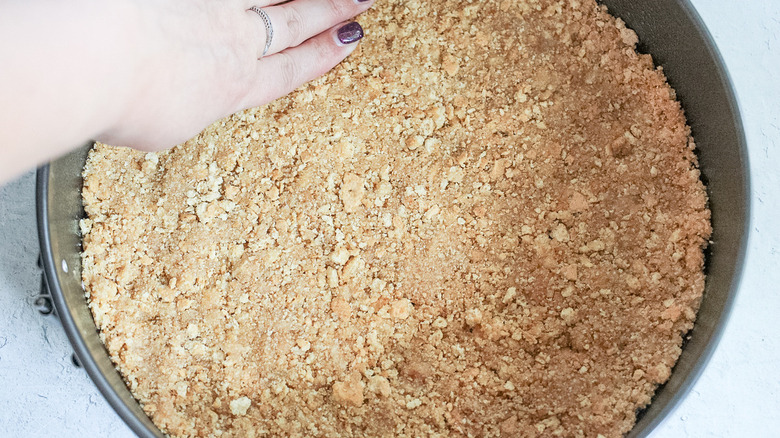 hand pressing pie crust into tin