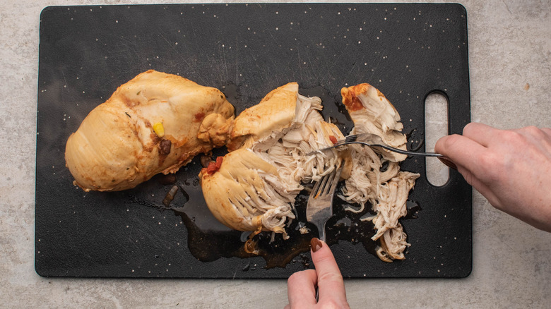 shredding chicken on cutting board
