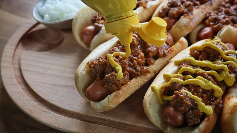 topping Coney Island hot dogs with mustard