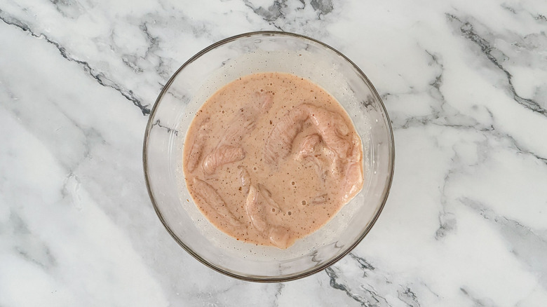 raw chicken marinating in bowl