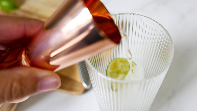 hand pouring gin into glass