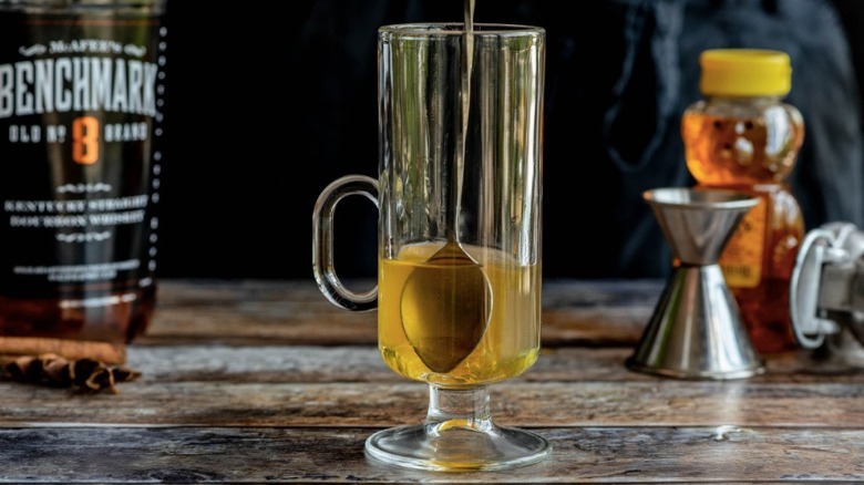 spoon stirring whiskey in glass mug