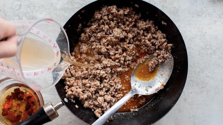 ground pork in skillet with broth