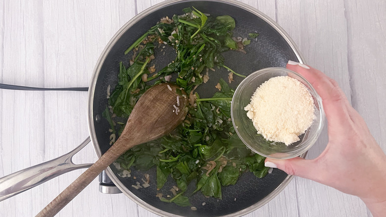 adding parmesan to wilted spinach