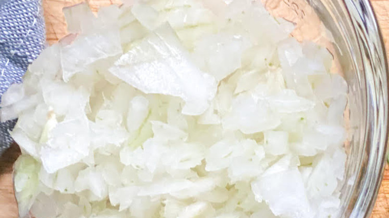 Overhead close up shot of a glass bowl filled with chopped up white onions