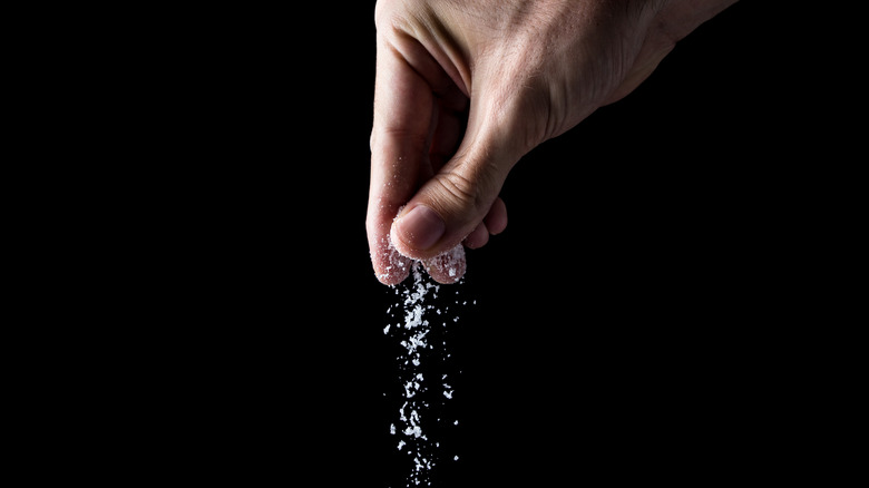 person sprinkling salt