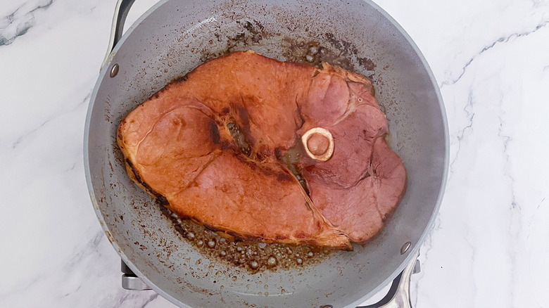 ham steak cooking in a skillet