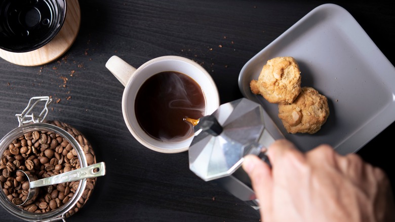 Hand pouring coffee into mug 