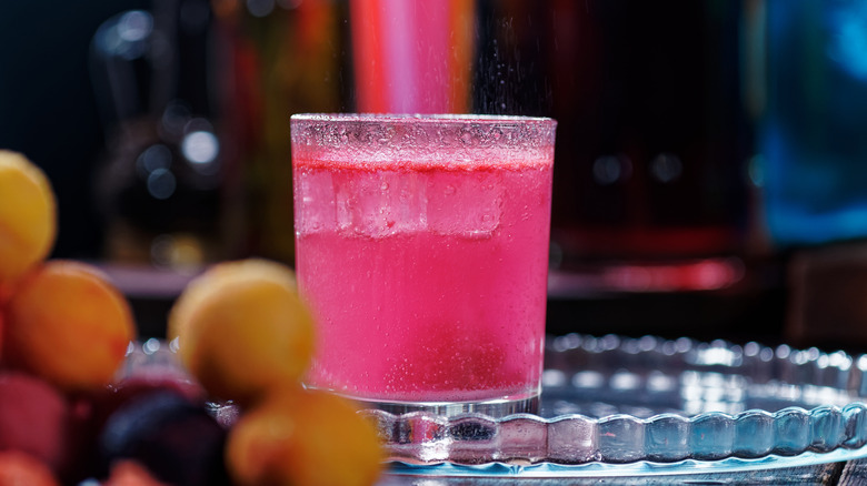 fizzy pink cocktail with blurred bombs in the background 