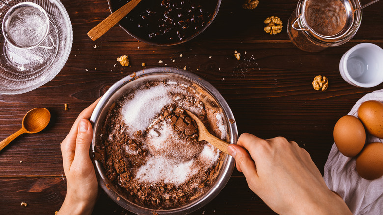 Person baking cake with baking ingredients on table