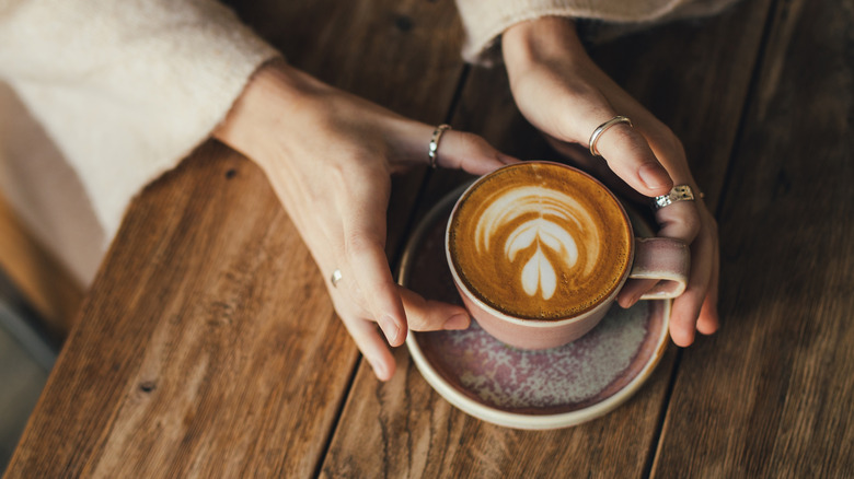 person picking up cup of coffee