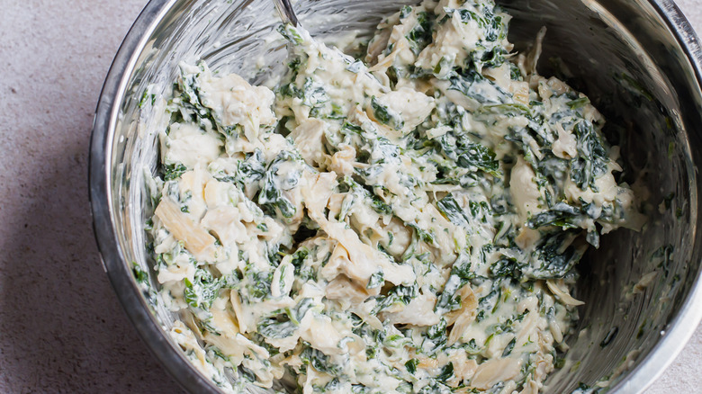 Mixing the spinach into the Cold Spinach Artichoke Dip Recipe