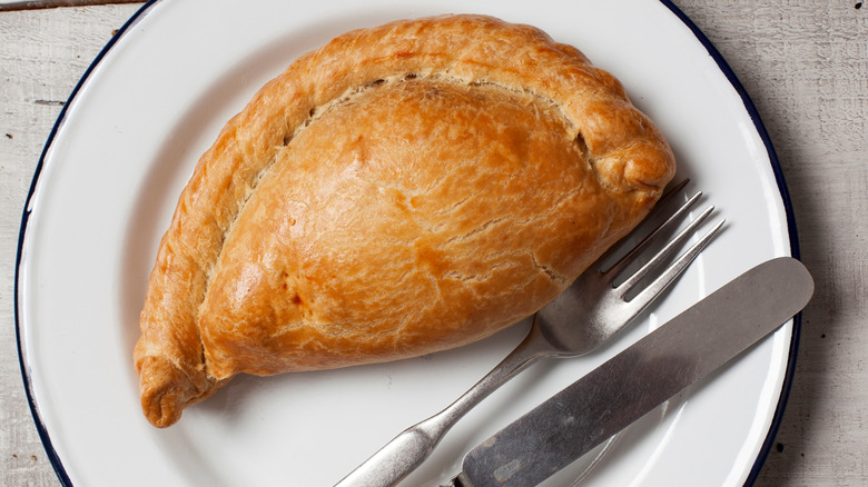 Pasty on a plate with knife and fork.