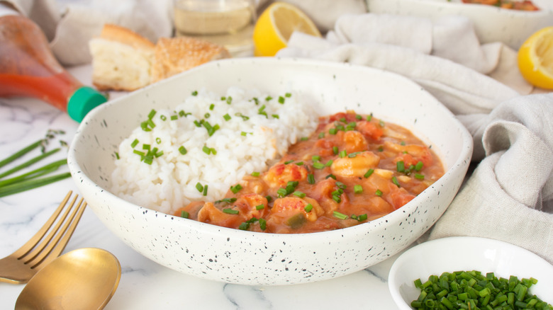 Rice and etouffee in bowl garnished with chives