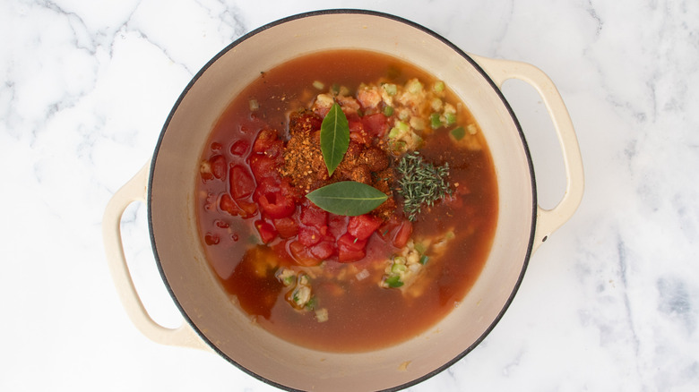 Tomato stew in pot with herbs and bay leaves