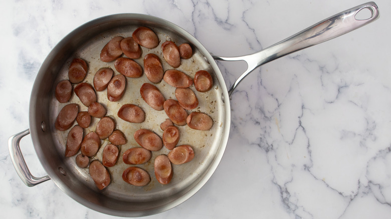 sliced hot dogs searing in skillet