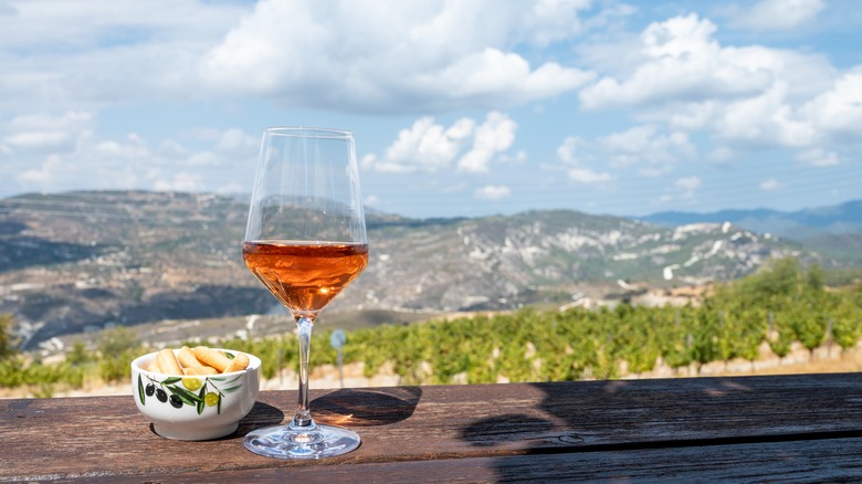 Commandaria in wine glass with backdrop of mountains and rolling hills