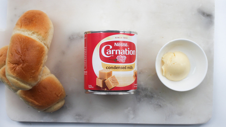 Brioche rolls, a can of condensed milk, and butter placed on a small container.