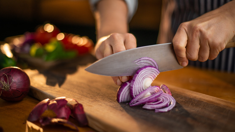 knife cutting red onions