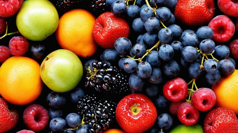 a selection of fruits includin blueberries, strawberries, oranges, and apples