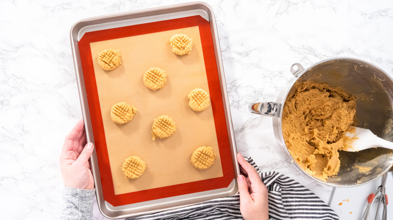 Hands holding cookie sheet with silicone mat