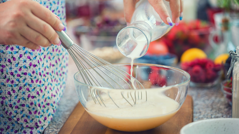 Person whisking milk into eggs