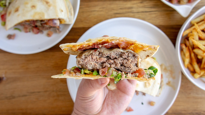 a quesadilla burger cut in half and held up to show the layers