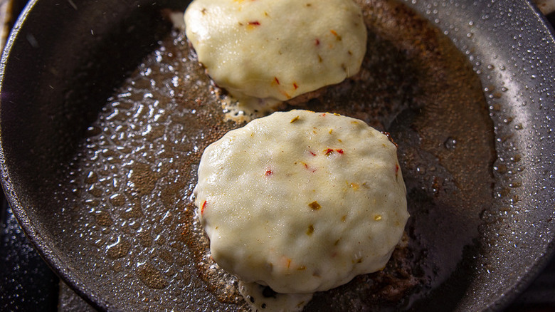 burgers with melted pepper jack cheese in a pan