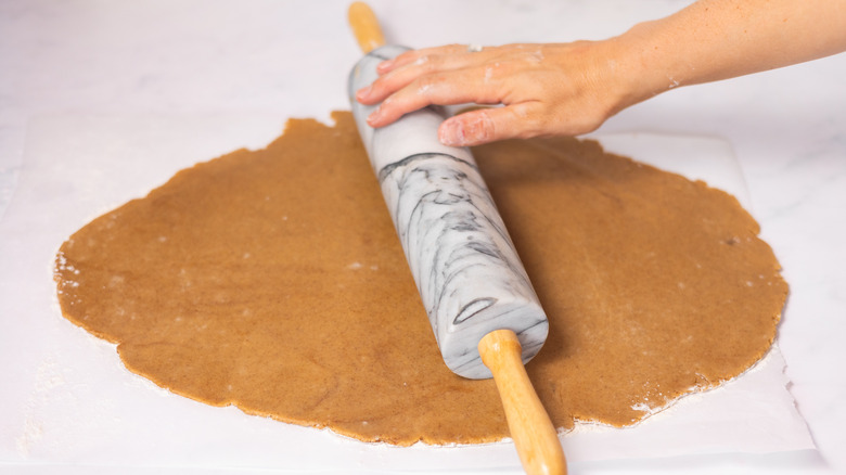 hand on rolling pin rolling out cookie dough 