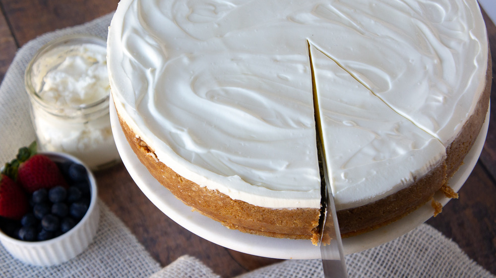 knife slicing into a whole cheesecake