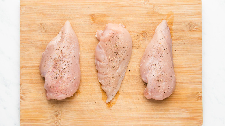 seasoned chicken breasts on chopping board
