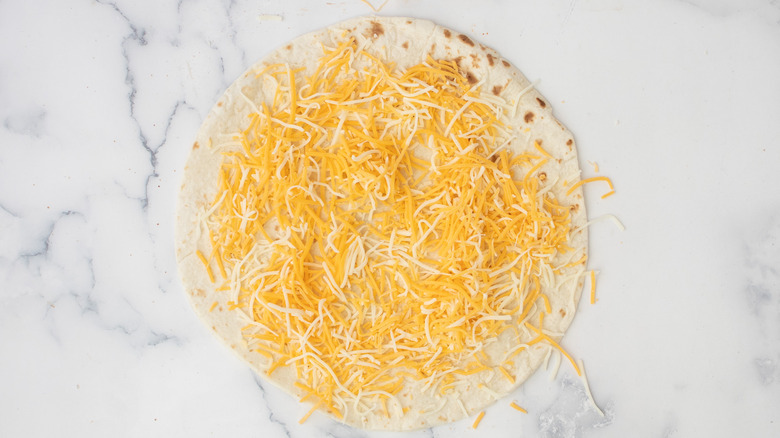 shredded cheese on tortilla