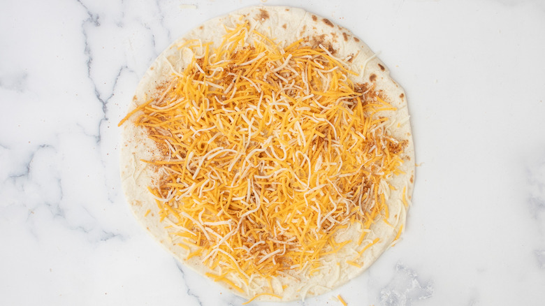 seasoned shredded cheese on tortilla