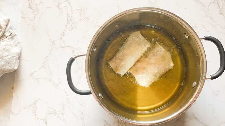 photo of egg rolls frying in a pot