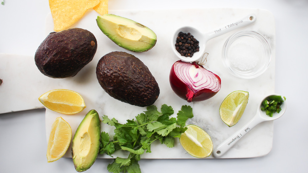 guacamole ingredients on white stone cutting board